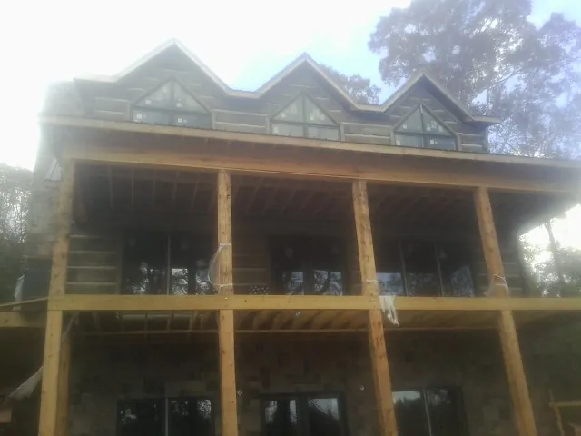Dormers and porch framing on a large log home under construction — Roof Coating work by our crew in Springer