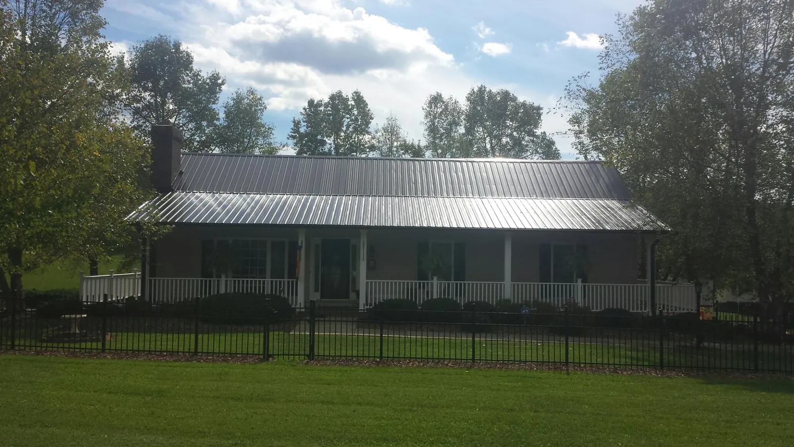 Gray metal roof on a brick ranch with a full width front porch — Gutter Guard Installation work by our crew in Springer