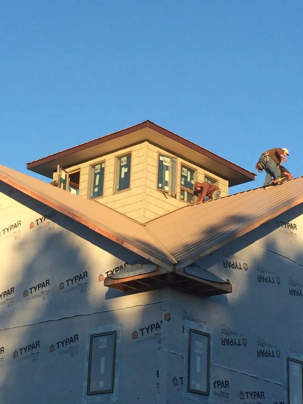 Roofers working around a rooftop cupola on a new metal roof at sunset — Roof Waterproofing in Springer by Roofing Brothers
